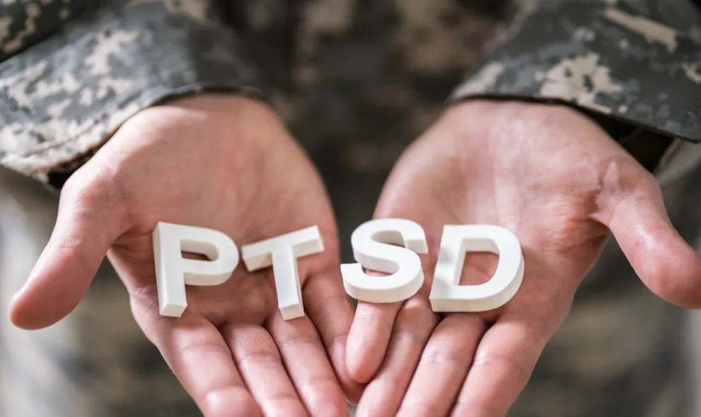 Male soldier holding wooden cubes with PTSD text