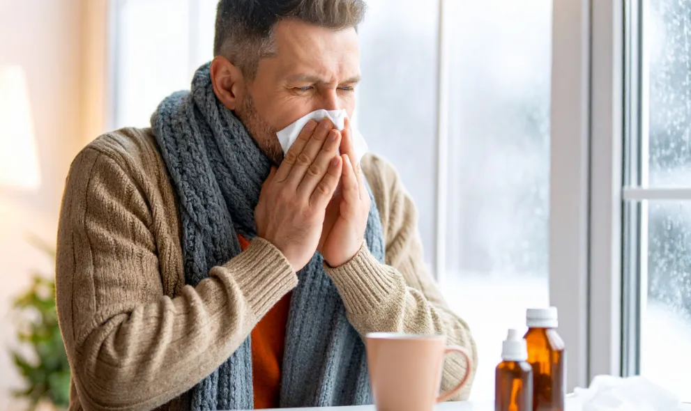 Man blowing nose with tissue due to illness