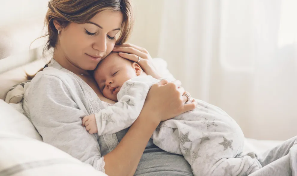 Mom holding baby laying on bed