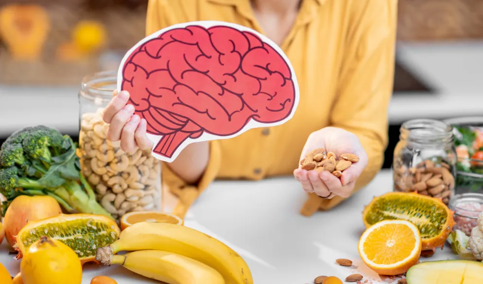 Woman holding human brain model with variety of healthy fresh food on table