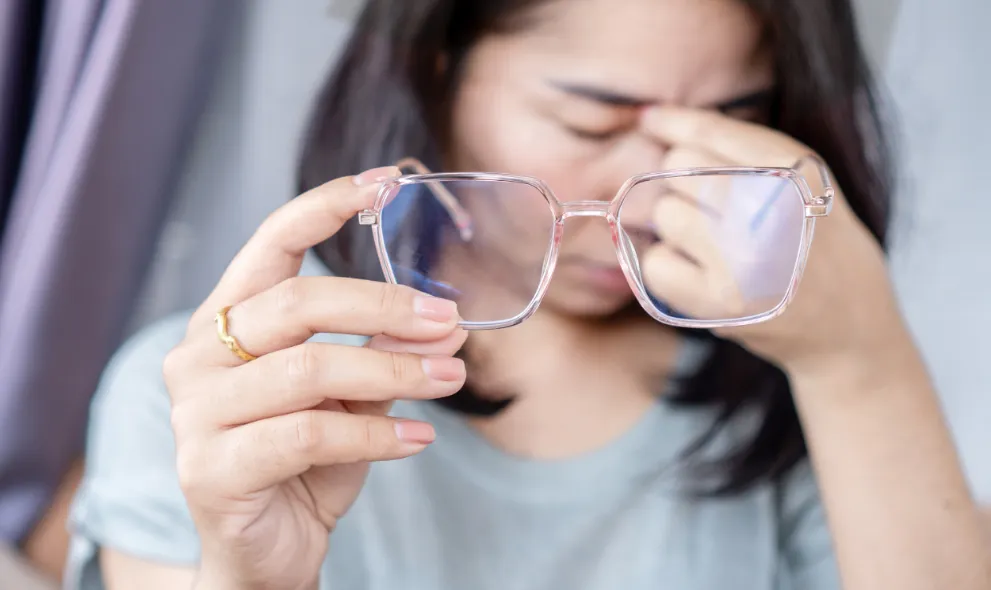 Woman suffering from blurry vision holding glasses